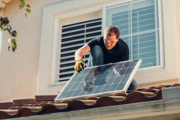 Solar technician installing a photovoltaic panel on a rooftop, promoting renewable energy.
