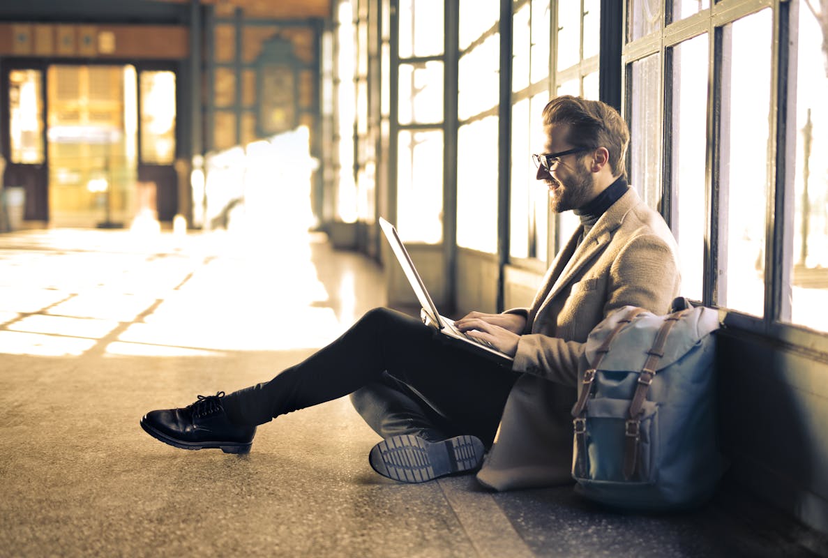 La FTTO Stelogy : l’internet ultra-performant taillé pour les pros Man sitting by a window at a Budapest train station, working on his laptop with sunlight streaming through.