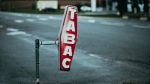 A vintage 'Tabac' sign on a street with blurred background, captured at dusk.