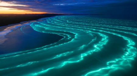 Illustration de la lueur turquoise bioluminescente au large de la côte sud de l'Australie, vue depuis l'espace, générée par intelligence artificielle.