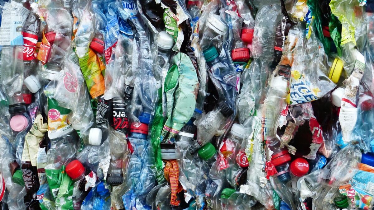 Balle compressée de bouteilles et emballages plastiques usagés, translucides et colorés, avec des logos de marques partiellement visibles.