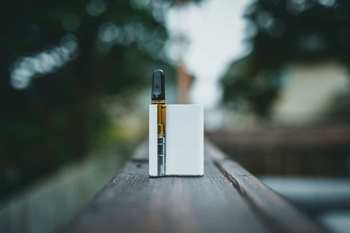 Grossiste biologique : ton partenaire pour des achats durables A sleek vape device resting on a wooden surface outdoors in natural light.