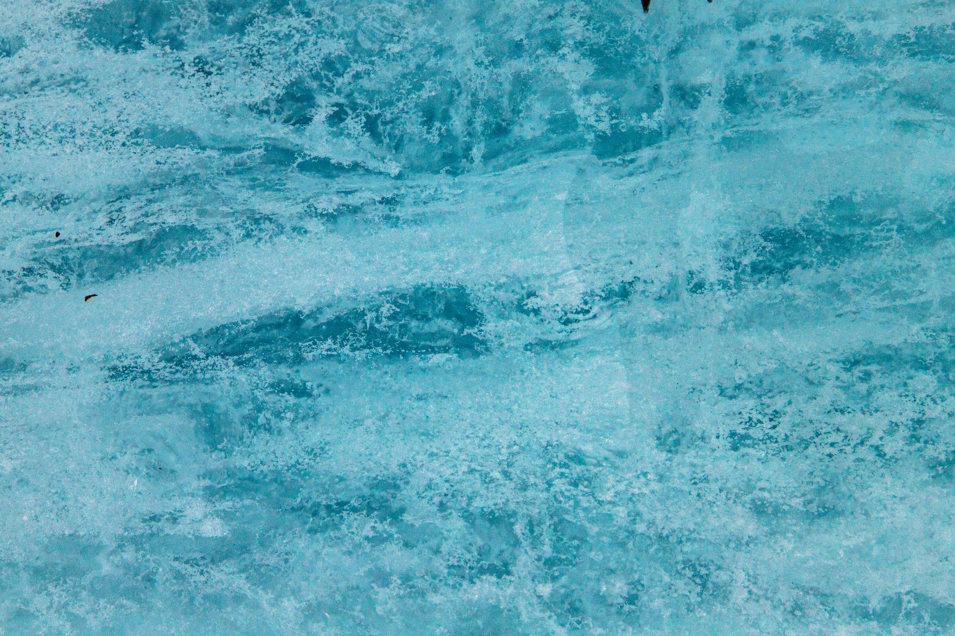 Gros plan sur la surface bleutée et texturée d’un bloc de glace glaciaire.